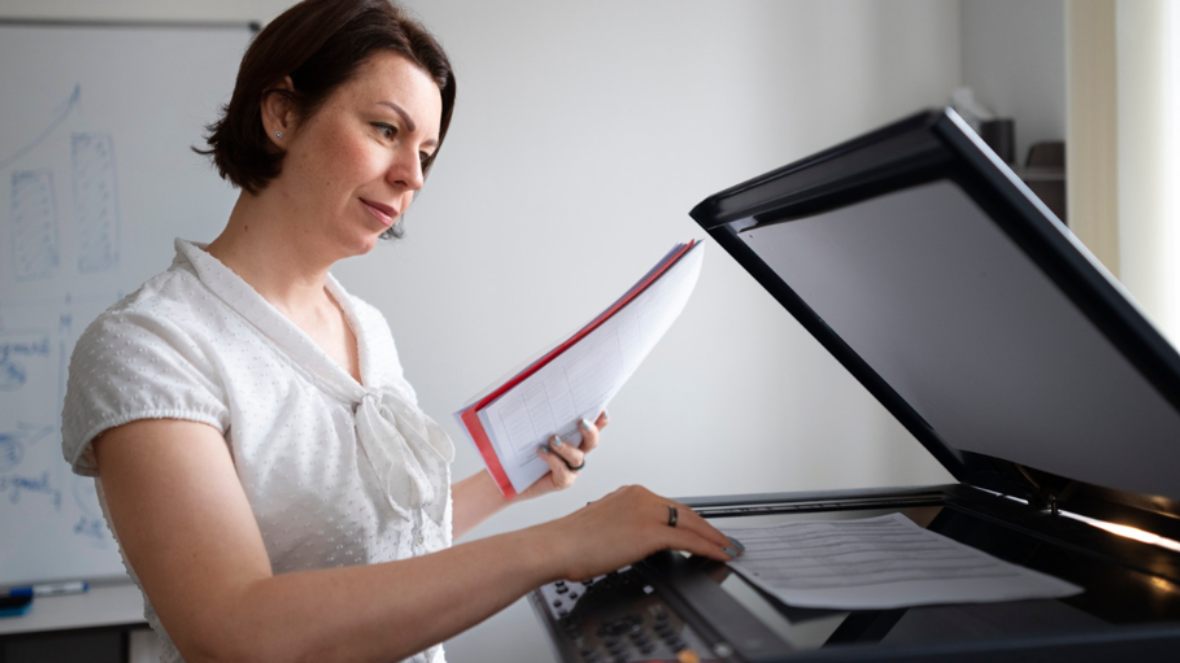 An office professional scanning corporate data sheets on a multi-function network laser printer, demonstrating secure document handling.