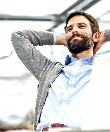 Man smiling with hands behind head