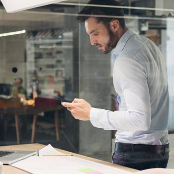 Printing when out of the office man using a smartphone while standing over desk